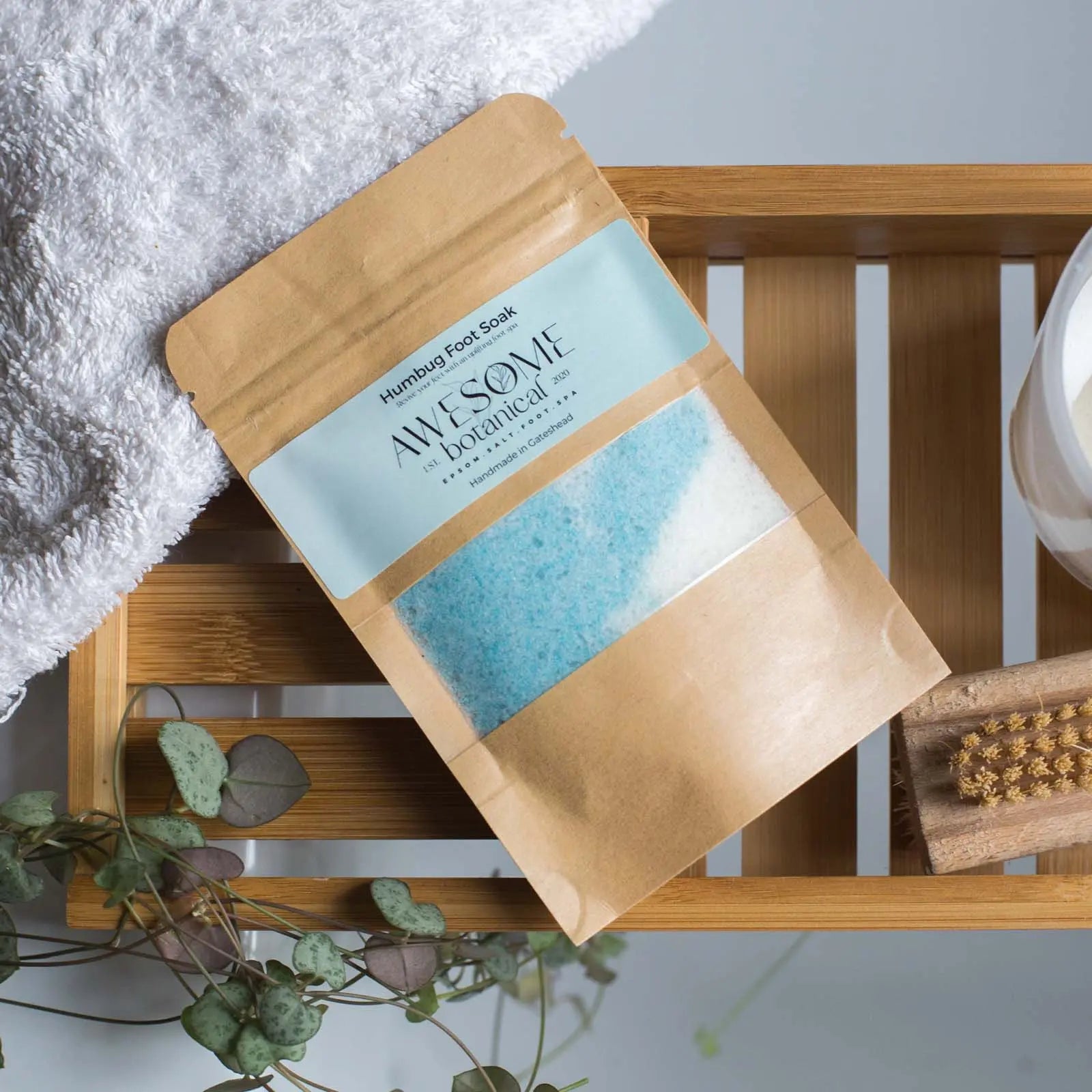 humbug epsom salt foot soak on bath rack with towel , leaves and nail brush