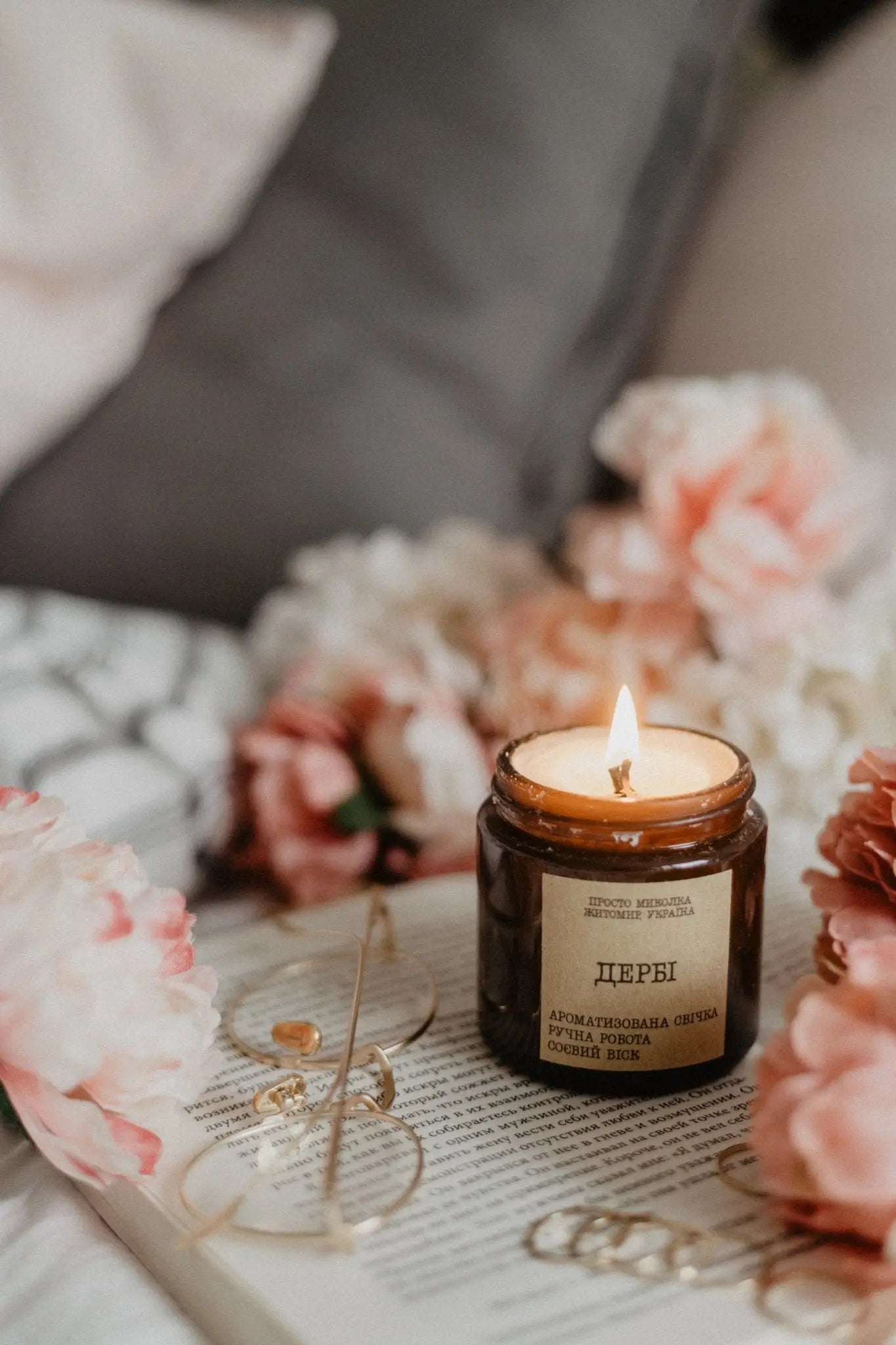 Lit candle on the side with flowers and a cushion