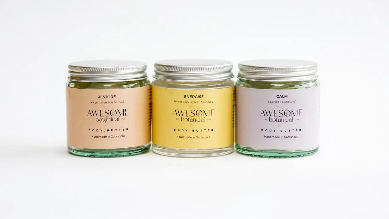 Energise Body Butter in hand with white flower background